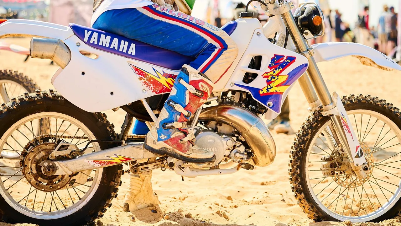 Yamaha PW 80 jaune et noire de profil sur un chemin de terre, mini-moto d'initiation des années 1990